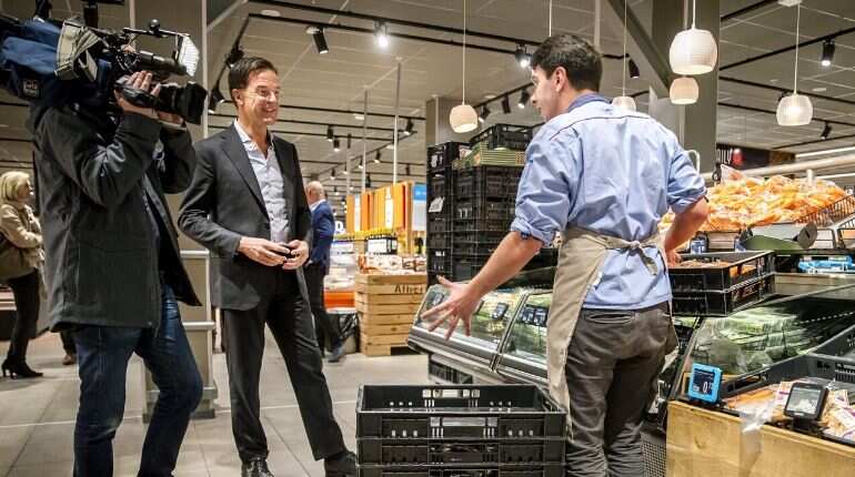 Prime Minister Mark Rutte (C) speaks with a worker in grocery store in The Hague, on March 19, 2020 amid the spread of the novel coronavirus