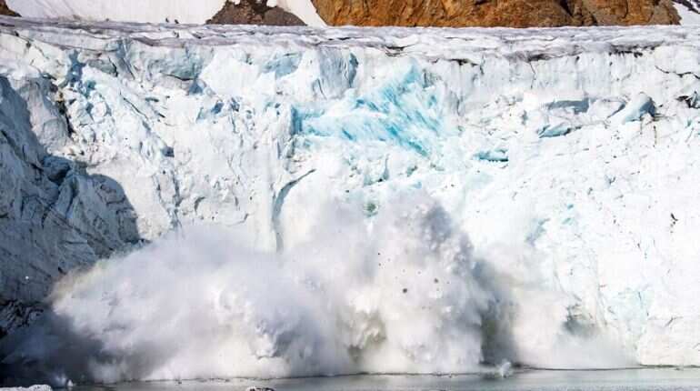A picture taken on August 17, 2019 shows an iceberg calving with a mass of ice breaking away from the Apusiajik glacier, near Kulusuk (aslo spelled Qulusuk), a settlement in the Sermersooq municipality located on the island of the same name on the southeastern shore of Greenland
