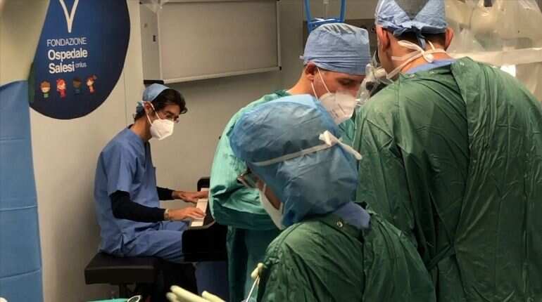 A still image taken from a video shows medical staff led by Dr. Roberto Trignani performing surgery to remove a double tumour in the spinal cord of a 10-year-old child as molecular biologist Emiliano Toso plays music on the piano with a frequency believed to have a therapeutic affect on the patient at the Salesi Pediatric Hospital in Ancona, Italy, November 16, 2020