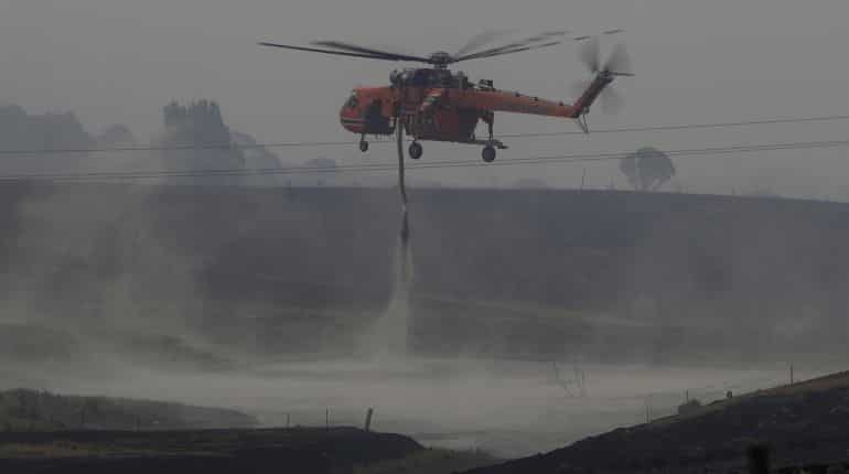 Firefighters spray water on smouldering patches left in the wake of a bushfire near Bumbalong, New South Wales, Australia, February 2, 2020.