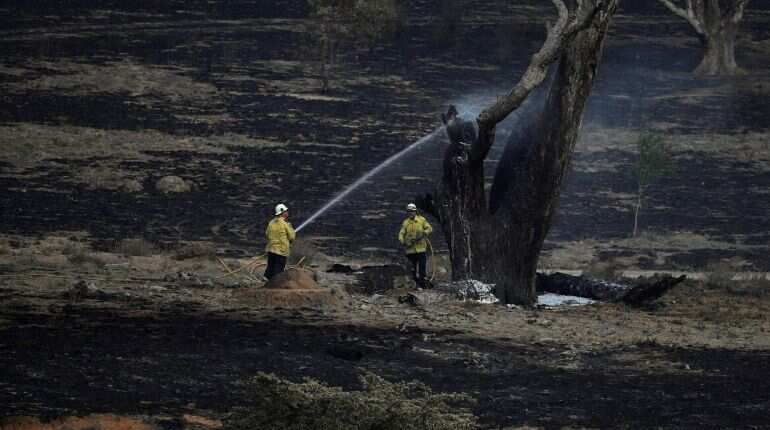 Firefighters spray water on smouldering patches left in the wake of a bushfire near Bumbalong, New South Wales, Australia, February 2, 2020.