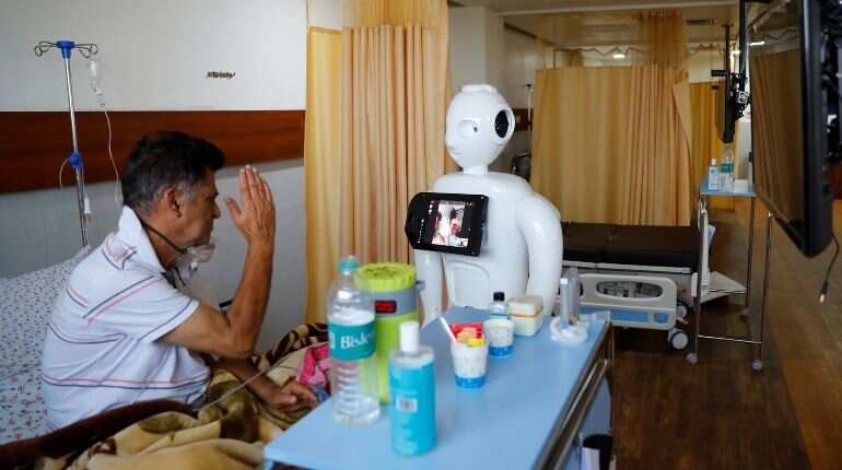A patient suffering from the coronavirus disease (COVID-19) speaks to his family members, using a robot named