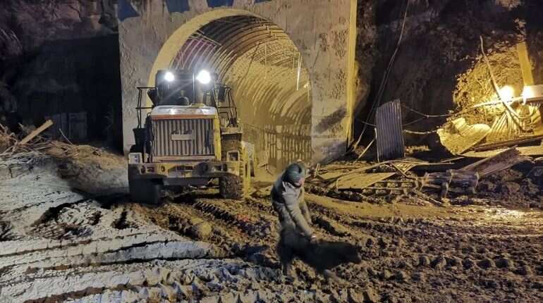 In this picture taken on February 8, 2021 an army personnel interacts with a stray dog called Blackie near the entrance of Tapovan tunnel, where dozens are still feared to be trapped following a flash flood thought to have been caused when a glacier broke off on February 7. "The dog has been roaming near the tunnel and was likely someone
