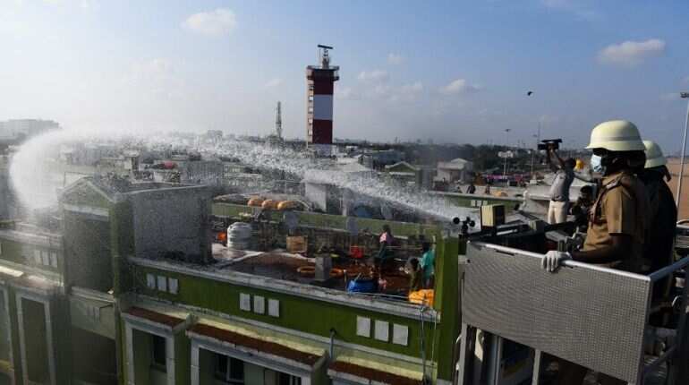 Firefighters spray disinfectant over a residential area from a sky lift crane during a government-imposed lockdown