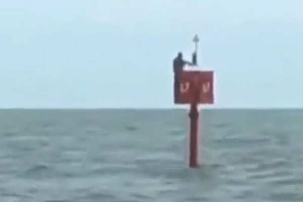 Brazilian fisherman clinging to ocean buoy