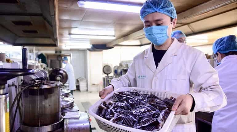 This photo taken on February 20, 2020 shows a medical worker holding bags of liquid traditional Chinese medicine at a hospital in Shenyang in China
