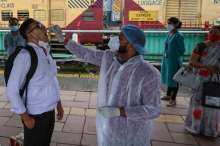 A health worker takes a swab sample of a passenger for the Covid-19  after arrival at a railway platform in Mumbai