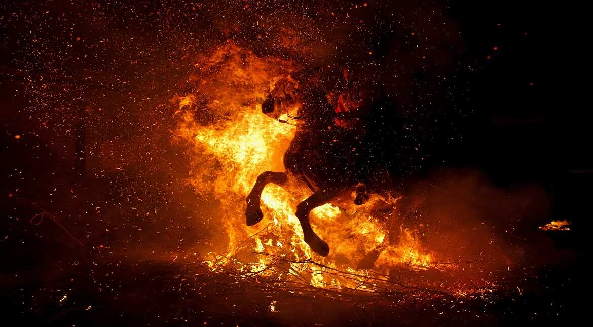 A woman rides a horse through a bonfire during 'Las Luminarias' Festival in San Bartolome de Pinares, Spain.