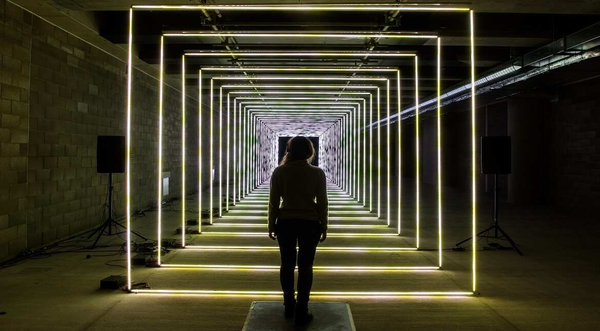 A woman interacts with 'On Your Wavelength' by Marcus Lyall at Canary Wharf in London, England.