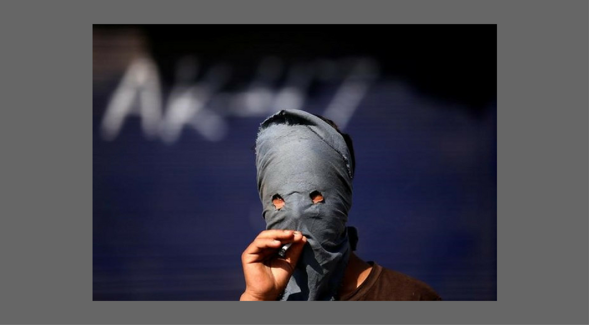 A masked Kashmiri demonstrator smokes a cigarette during a protest against the recent killing of a civilian, in Srinagar