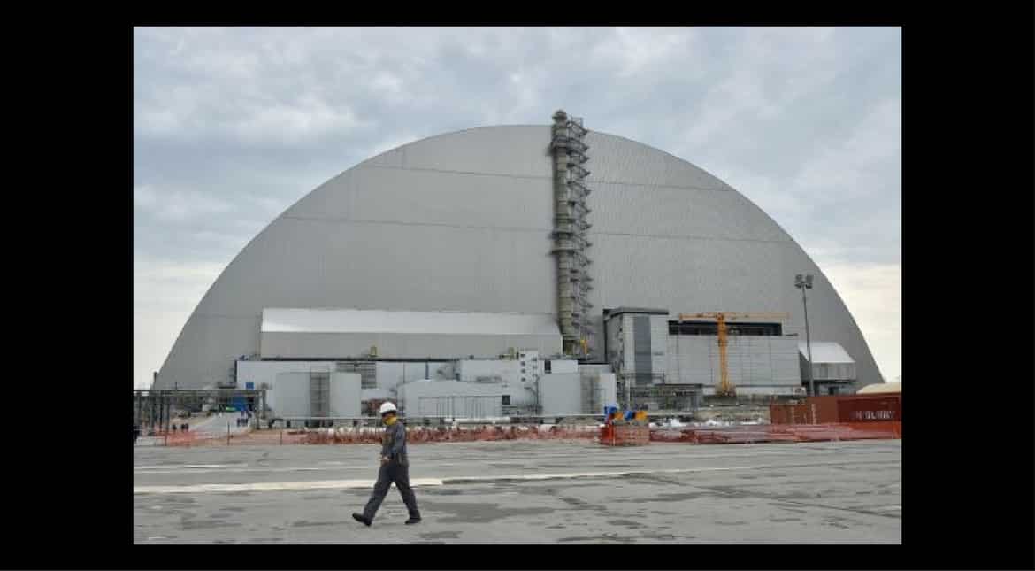 Workers walk next to the New Safe Confinement over the Chernobyl nuclear plant on April 26, 2017, the 31st anniversary of the disaster