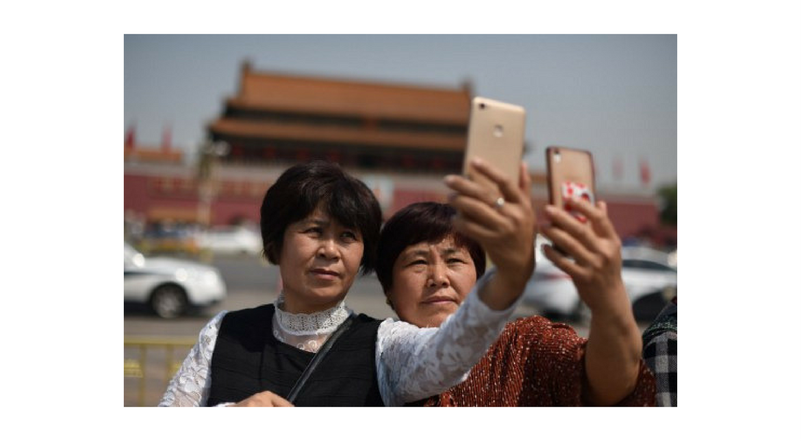 Visitors pose for photos in Tiananmen Square on the May Day holiday in Beijing on May 1, 2017.