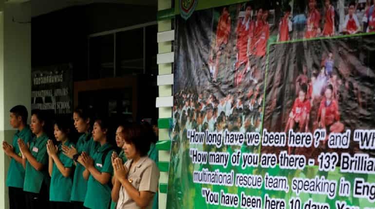 Schoolmates pray next to a banner