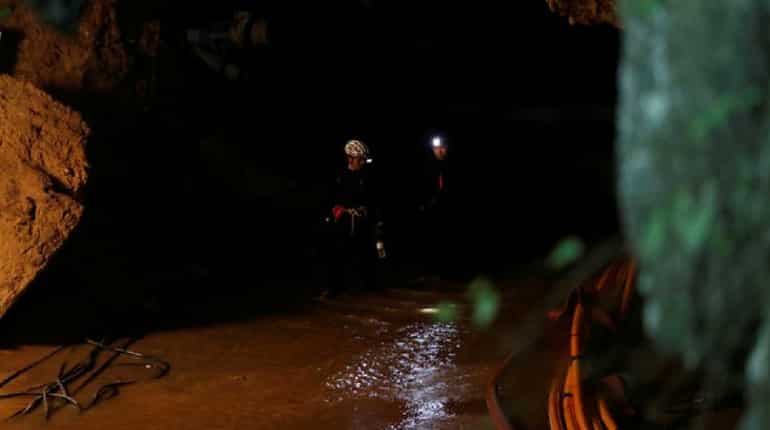 Divers walk inside Tham Luang cave complex