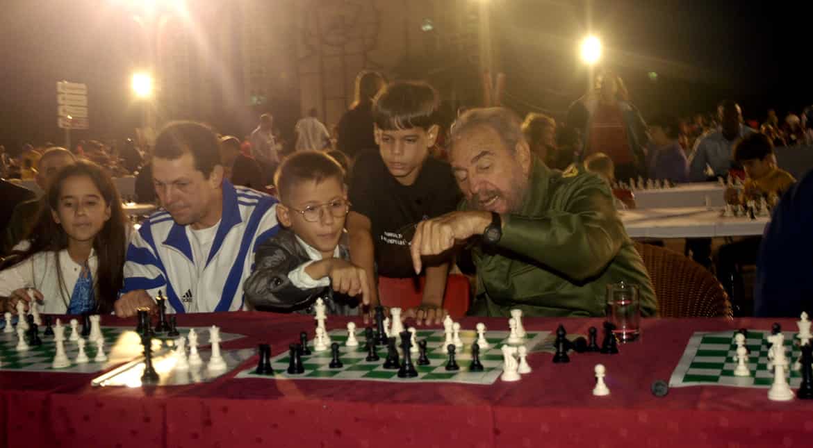 Fidel shares a light moment with children playing chess during a simultaneous game with about 11,000 people on December 7, 2002 in Havana.