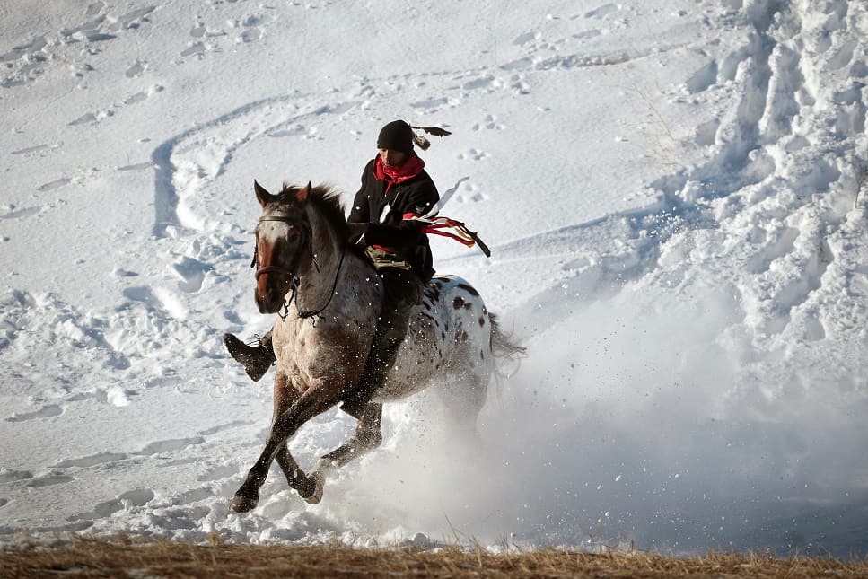 An Native American activist rides down fom a ridge which overlooks Oceti Sakowin