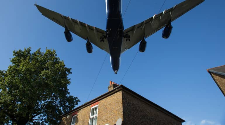 A passenger aircraft passes over a residential house as it prepares to land at London Heathrow Airport in west London.