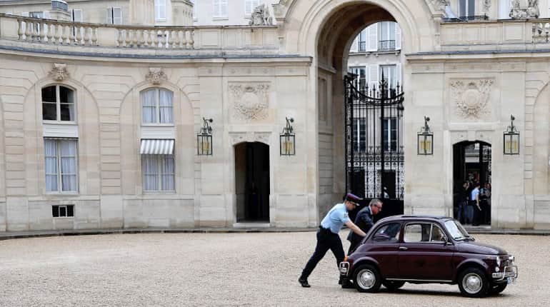 Staff push a Fiat 500 that does not start in the courtyard of the Elysee presidential palace.