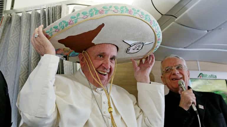 Pope Francis wears a traditional Mexican sombrero hat received as a gift by a Mexican journalist aboard the plane to Havana.