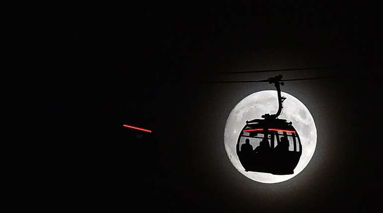 The moon rises behind a car on the The Emirates Air Line (cable car) in London's Docklands.