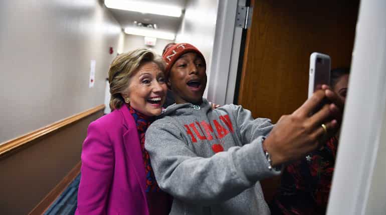 US Democratic presidential nominee Hillary Clinton poses with singer Pharrell Williams for a selfie backstage before a campaign rally in Raleigh.