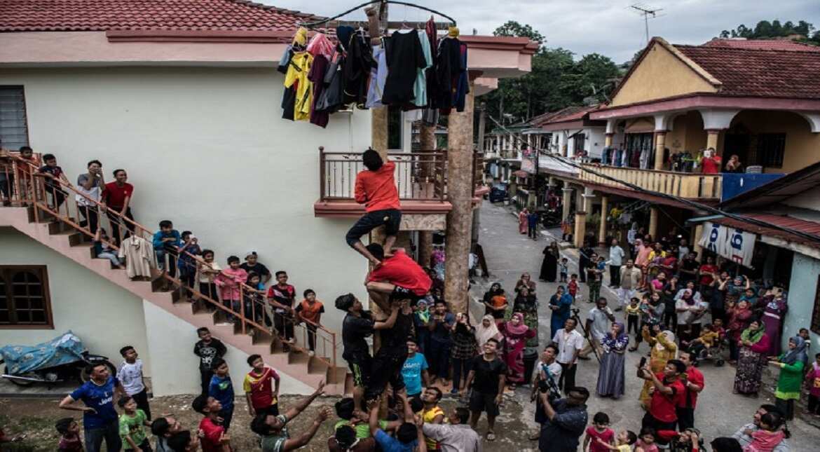 Malaysian children from the ethnic Indonesian Bawean community compete for prizes by climbing a pole called