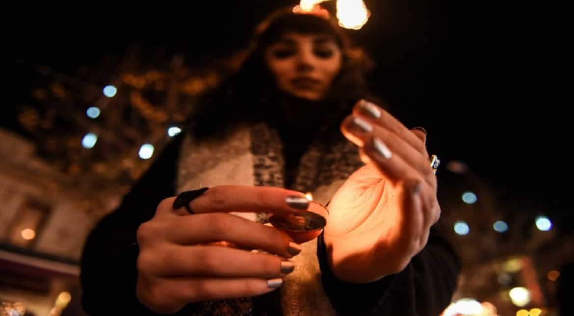 A woman lights a candle at a makeshift memorial tribute in Prizren in tribute to the victims