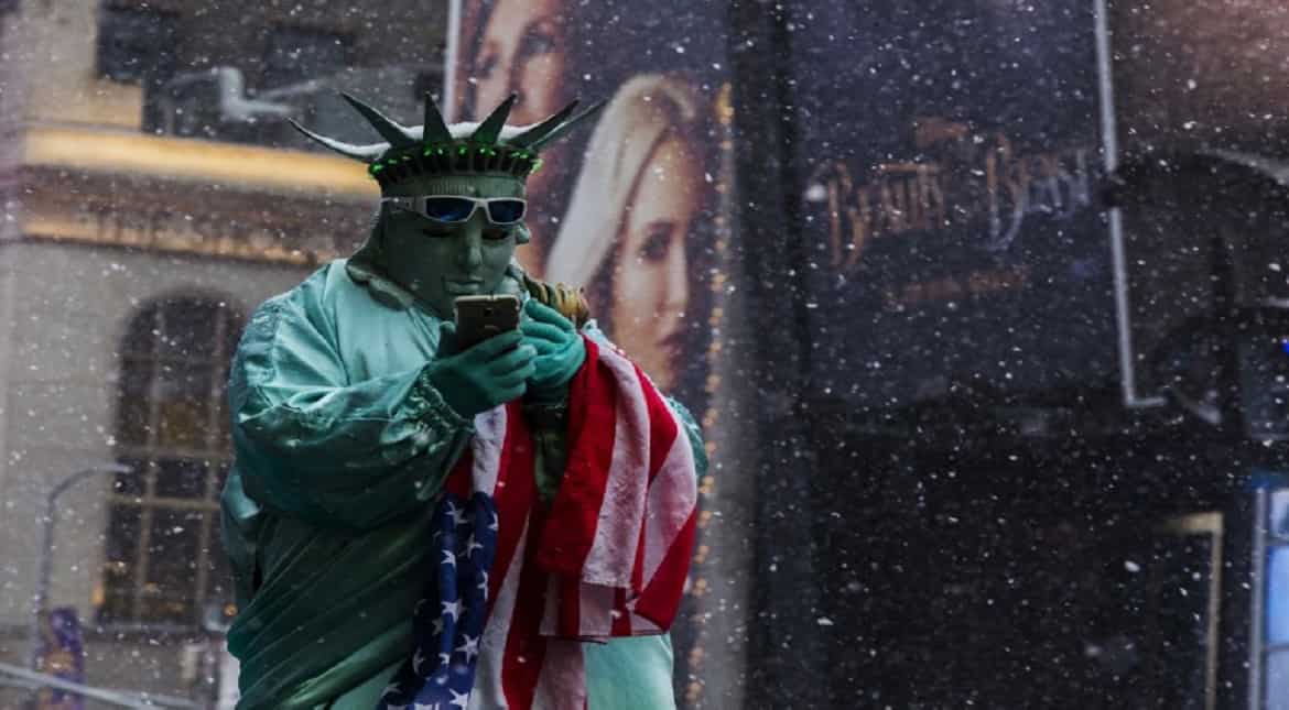 A man in costume waits for tourists to take picture with him under a snowfall in Times Square during a winter storm in New York.