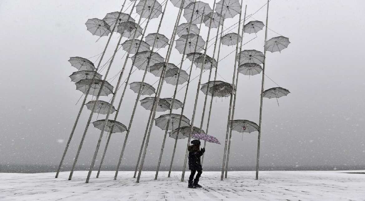 A woman holding an umbrella walks under Greek sculptor artist George 'Zongolopoulos Umbrellas'