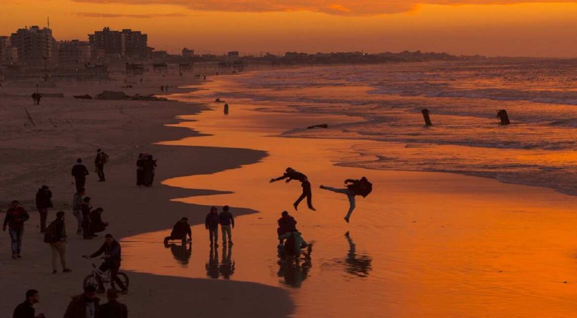 Palestinians make jumps on the beach during the sunset in Gaza City.