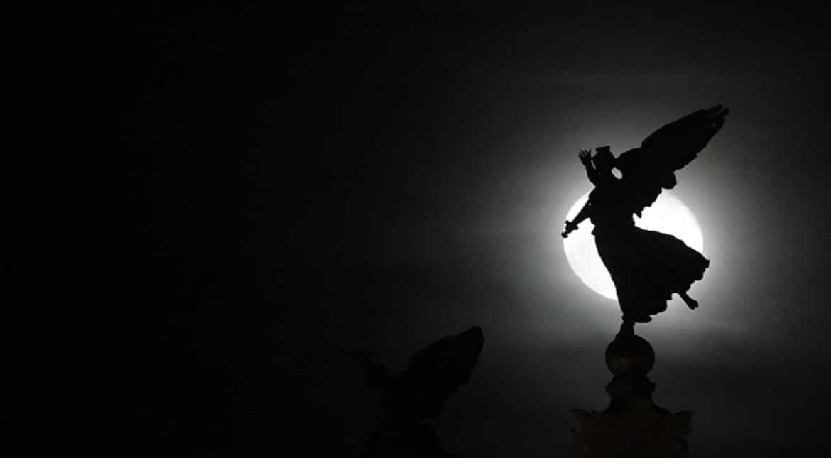 The moon is seen behind Vittoriano statue in central Rome.