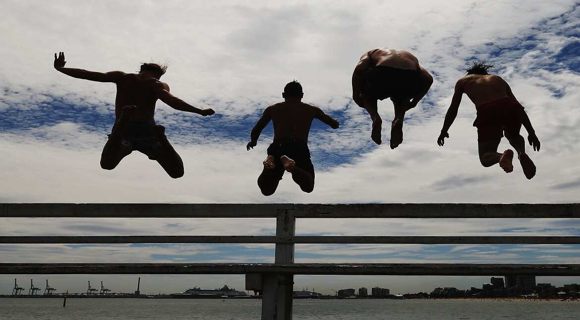 Beach goers jump off the pier at South Melbourne Beach in Melbourne, Australia.