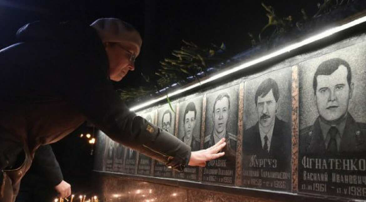 A woman touches a portrait during a memorial ceremony early on April 26, 2017, at the monument to Chernobyl victims in Slavutich