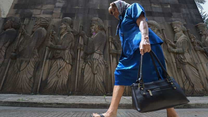 An elderly Indian Parsi woman walks past relief figures of knights at a Fire Temple during Navroze, the Parsi New Year, in Mumbai on August 17, 2017.