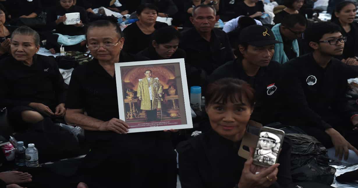 Mourners hold images of the late Thai King Bhumibol Adulyadej