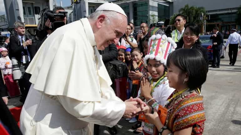 Pope Francis is greeted by young children in traditional clothes upon his arrival at Yangon's airport in Myanmar.