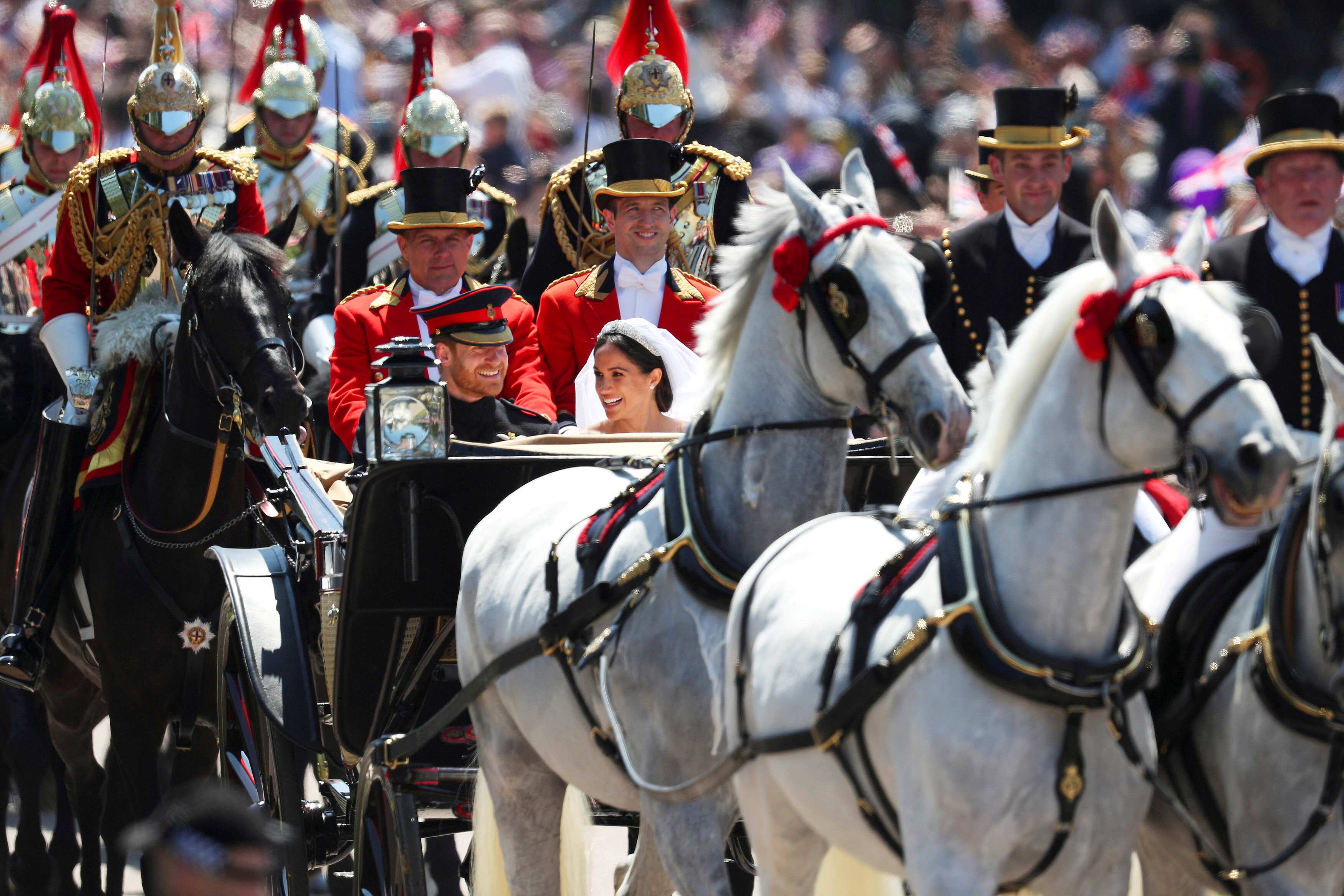 Britain's Prince Harry and his wife Meghan Markle ride a horse-drawn carriage
