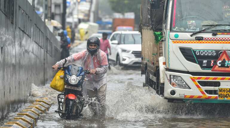 People make way through a flooded road after heavy rain