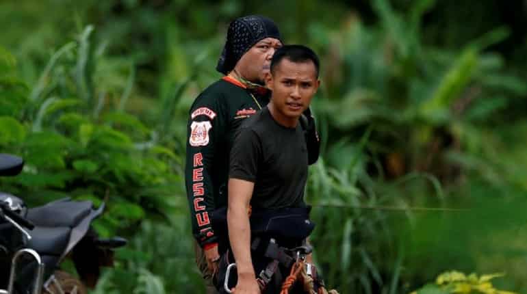 Cavers walk on a road leading to the Tham Luang cave complex,