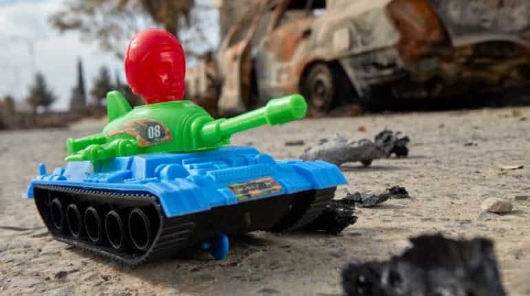 A toy tank arranged near a destroyed car