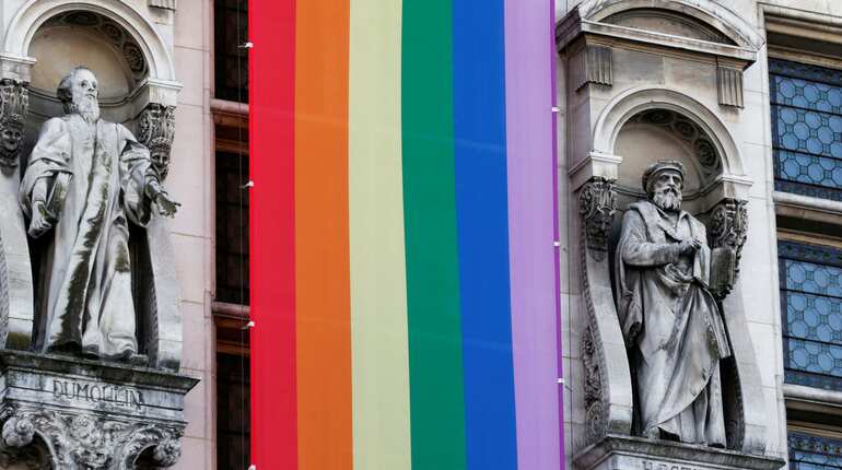 A long rainbow flag is displayed on the facade of Hotel de ville city Hall