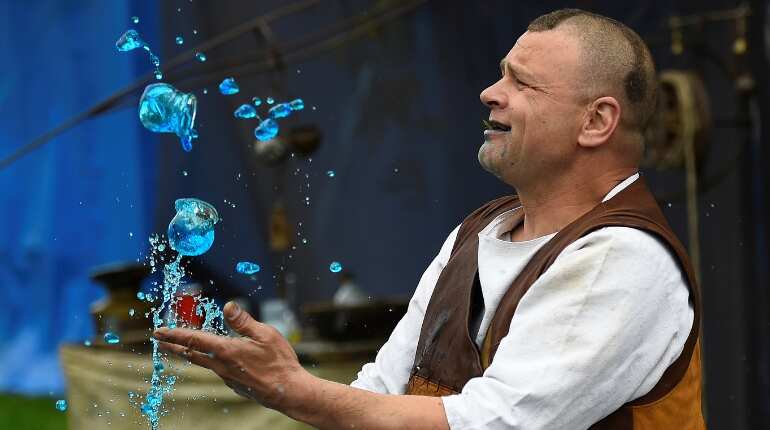 A man dressed as an alchemist demonstrates chemical tricks with bottles of liquids