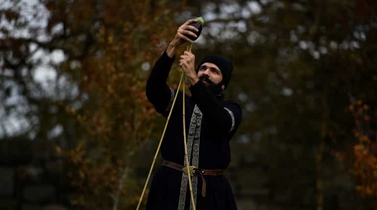 A man dressed as an Ottoman warrior skewers an aubergine onto posts for riders to demonstrate sword skills