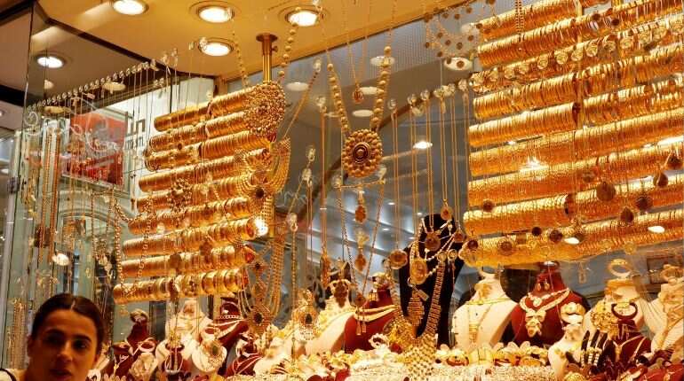 Gold edges lower as dollar firms; weaker equities limit losses