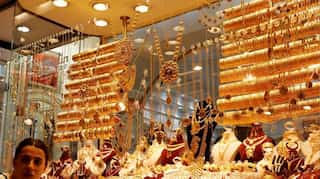 Gold edges lower as dollar firms; weaker equities limit losses