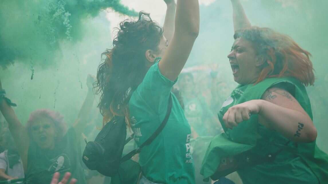 Women release colored smoke as they take part in a demonstration