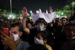 Protesters scale monument, turn their back on King's motorcade in Thailand