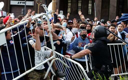Fans confront riot police as millions gather to pay last respects to Maradona