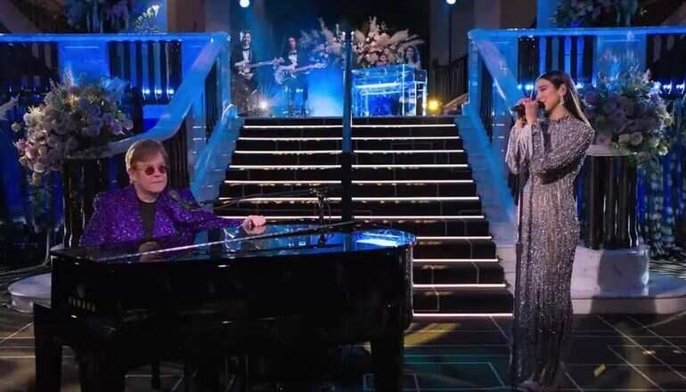 Dua Lipa sparkles in a metallic dress as she performs at Elton John's annual Oscar party