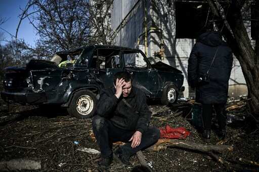 Man sits outside destroyed building